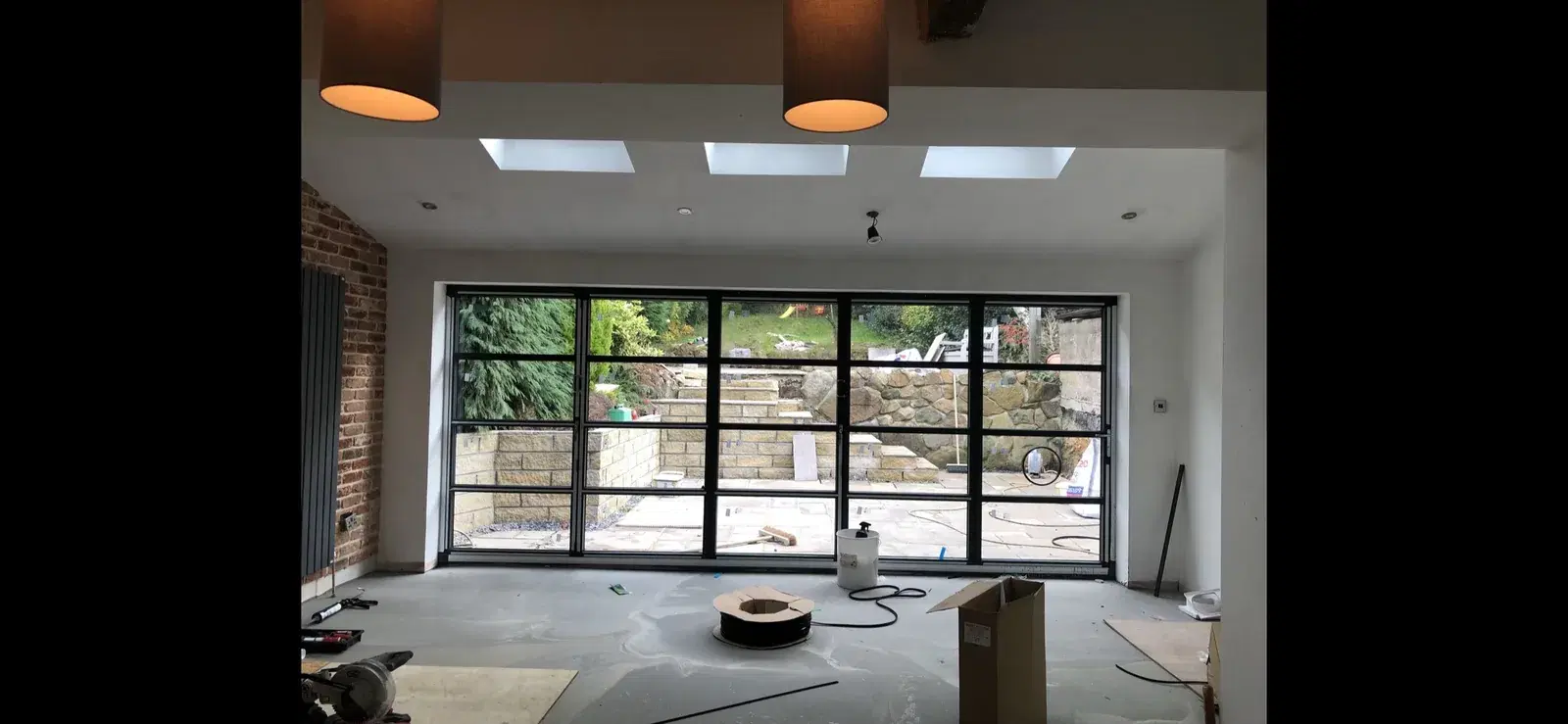 Georgian-bar bi-folding doors seen from inside a newly plastered room, looking out to a stone-terraced garden.