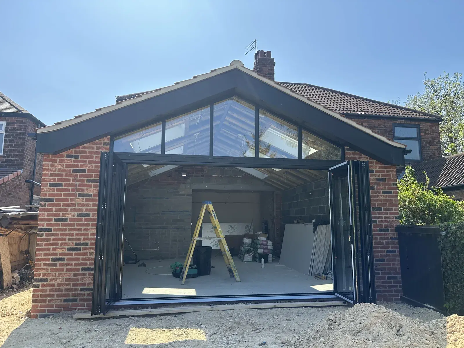 Bi-folding doors standing open in a brick extension below a glazed apex gable.