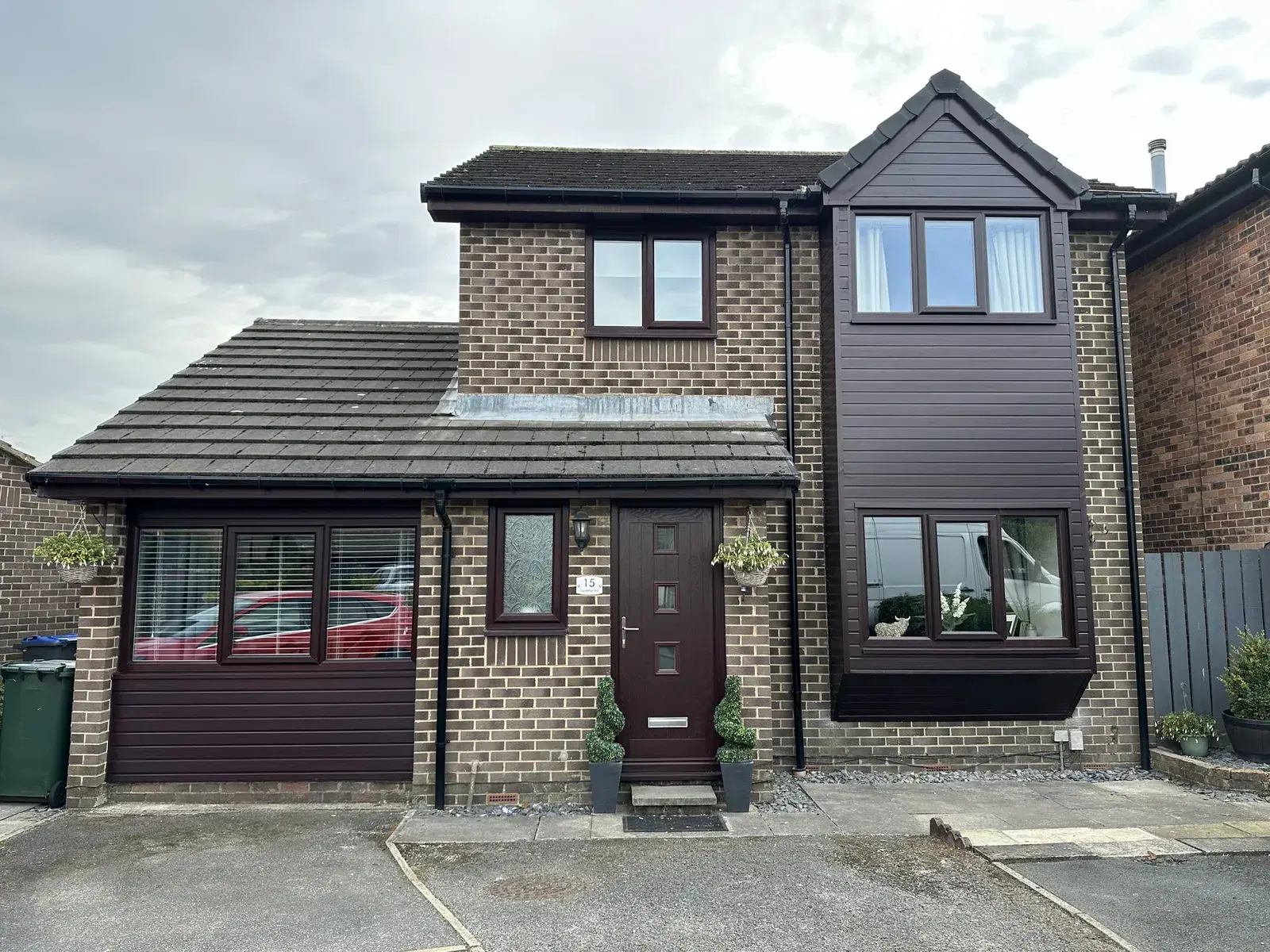 Burgundy UPVC casement windows and a matching composite door on a brick-built house.