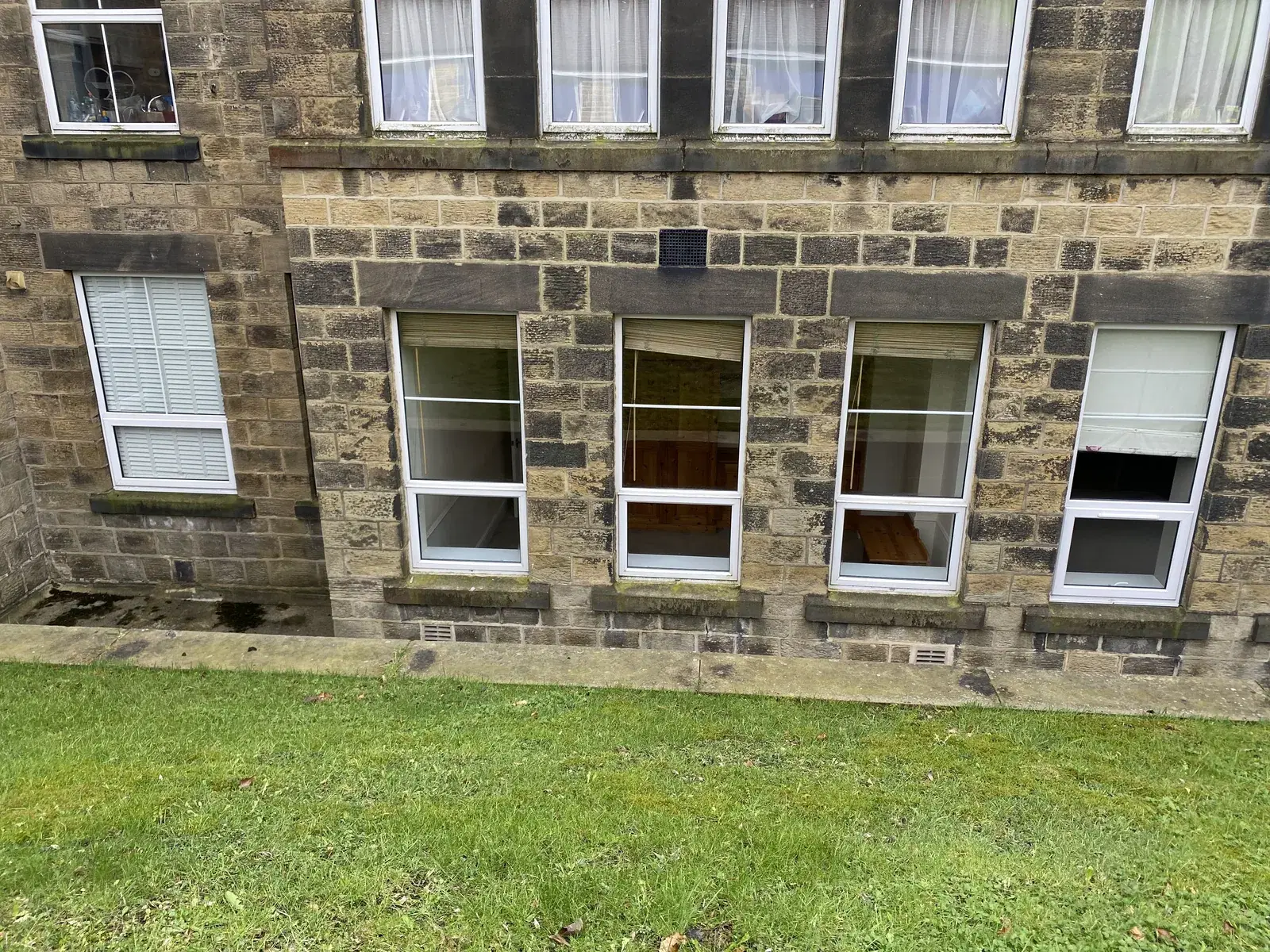 White casement windows fitted to the ground floor of a traditional stone building.