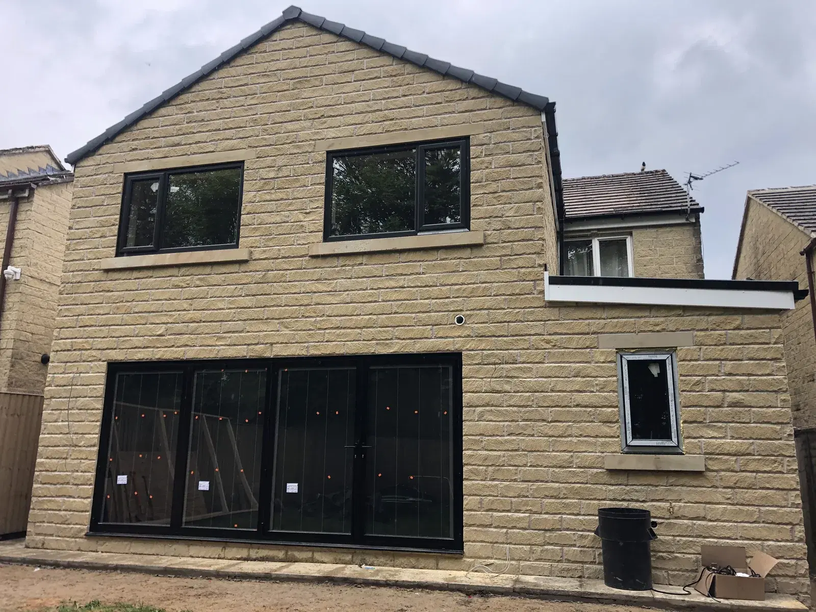 Black bi-folding doors and matching windows on a newly built stone house.