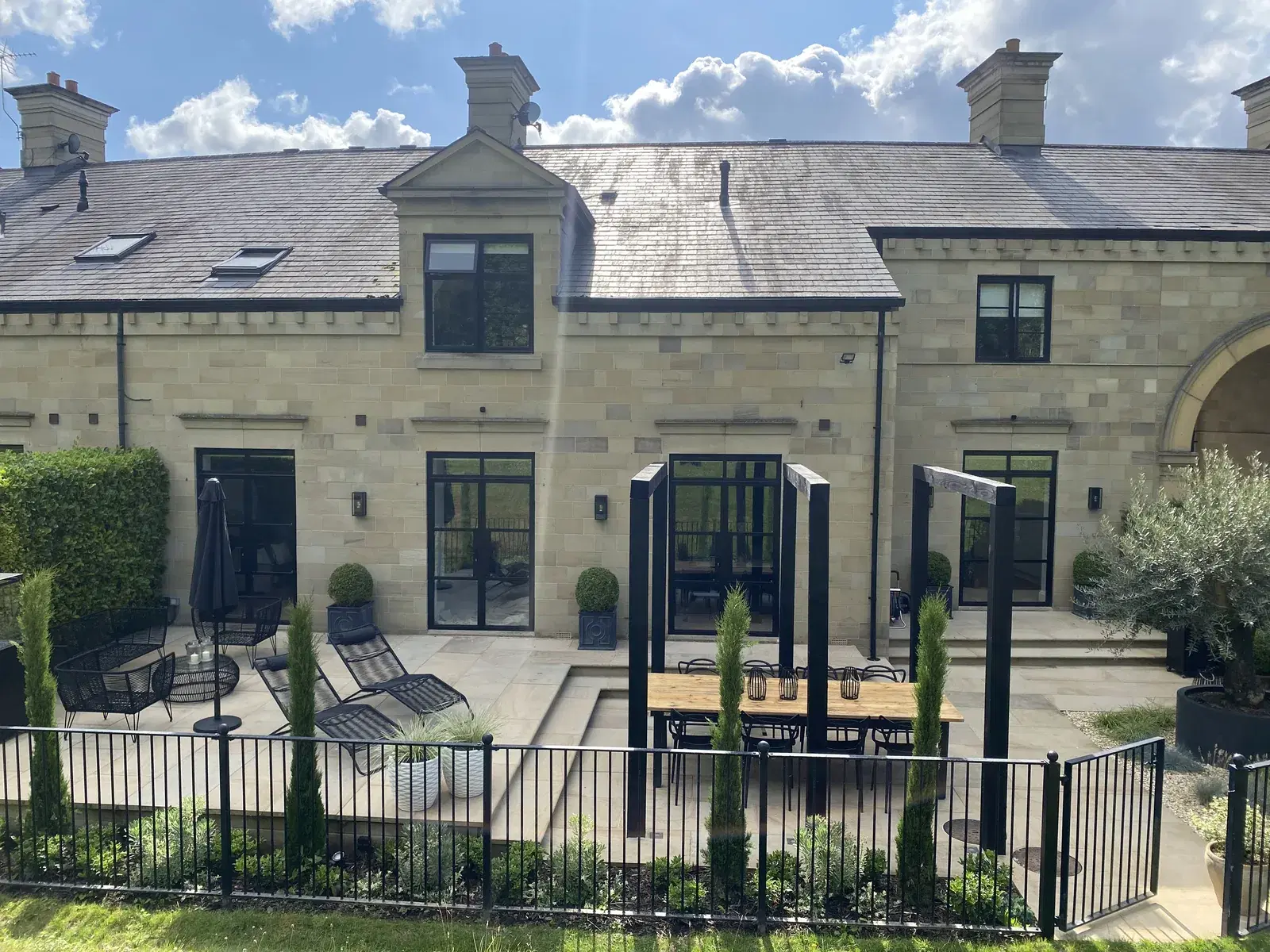 A barn-style property with black framed glazing opening onto a gravel terrace.