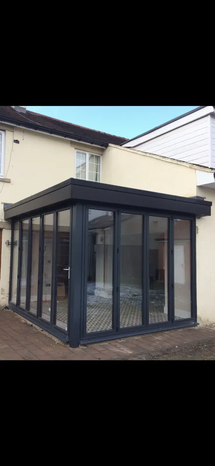 A glazed garden room with anthracite bi-folding doors wrapping two sides.