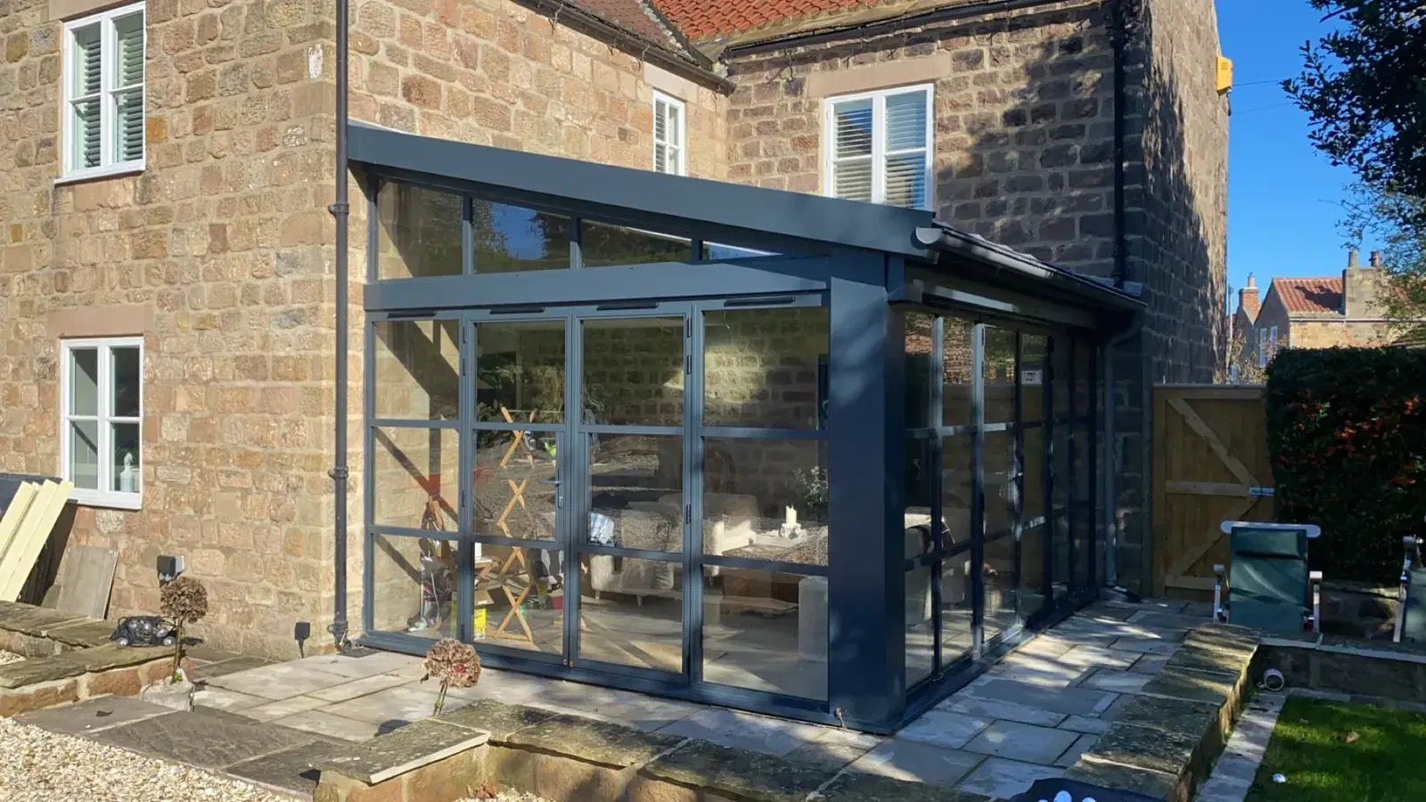 A stone-built house fitted with black aluminium windows throughout.
