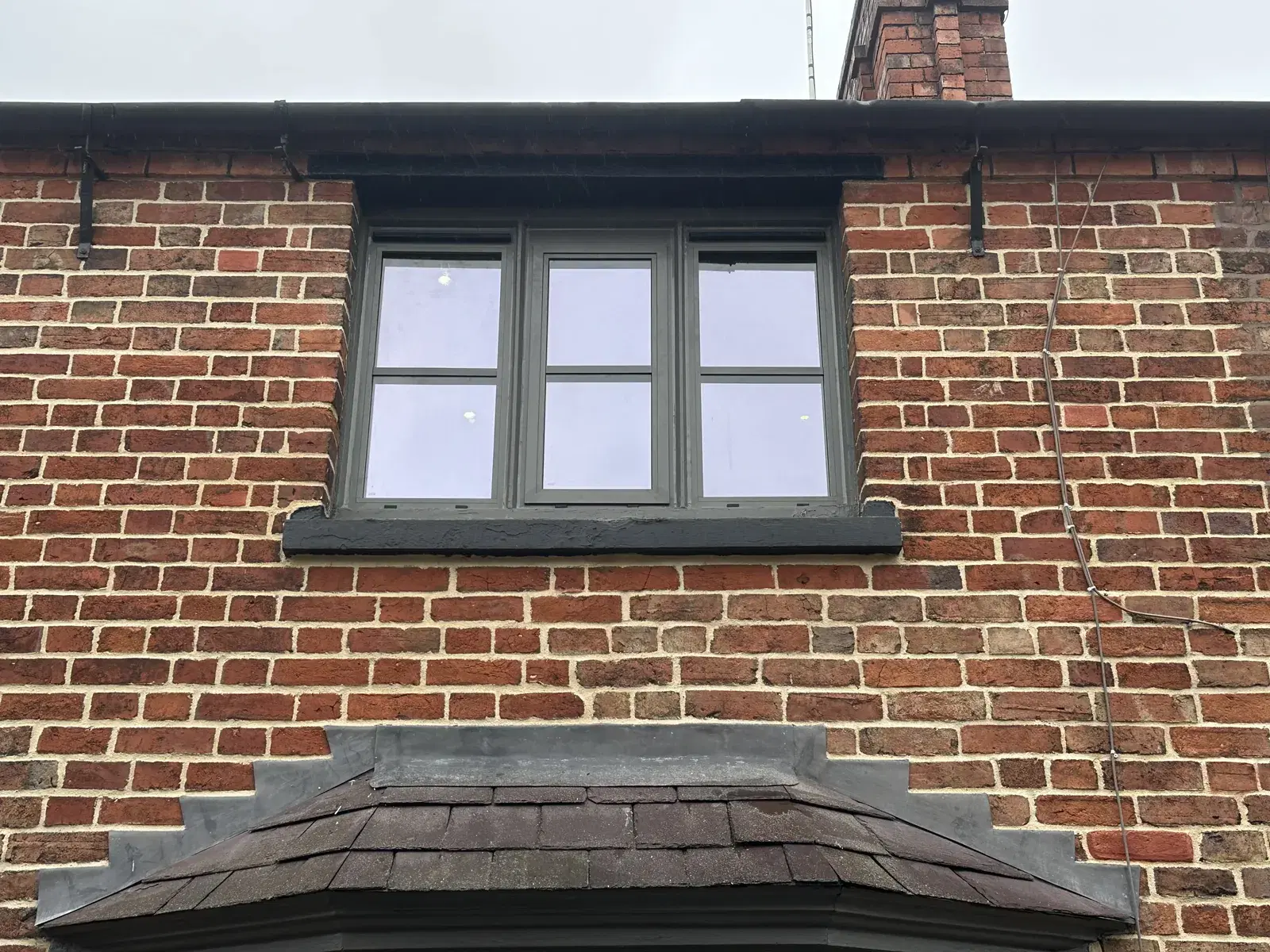 Heritage-style windows with slim black frames in a traditional stone elevation.