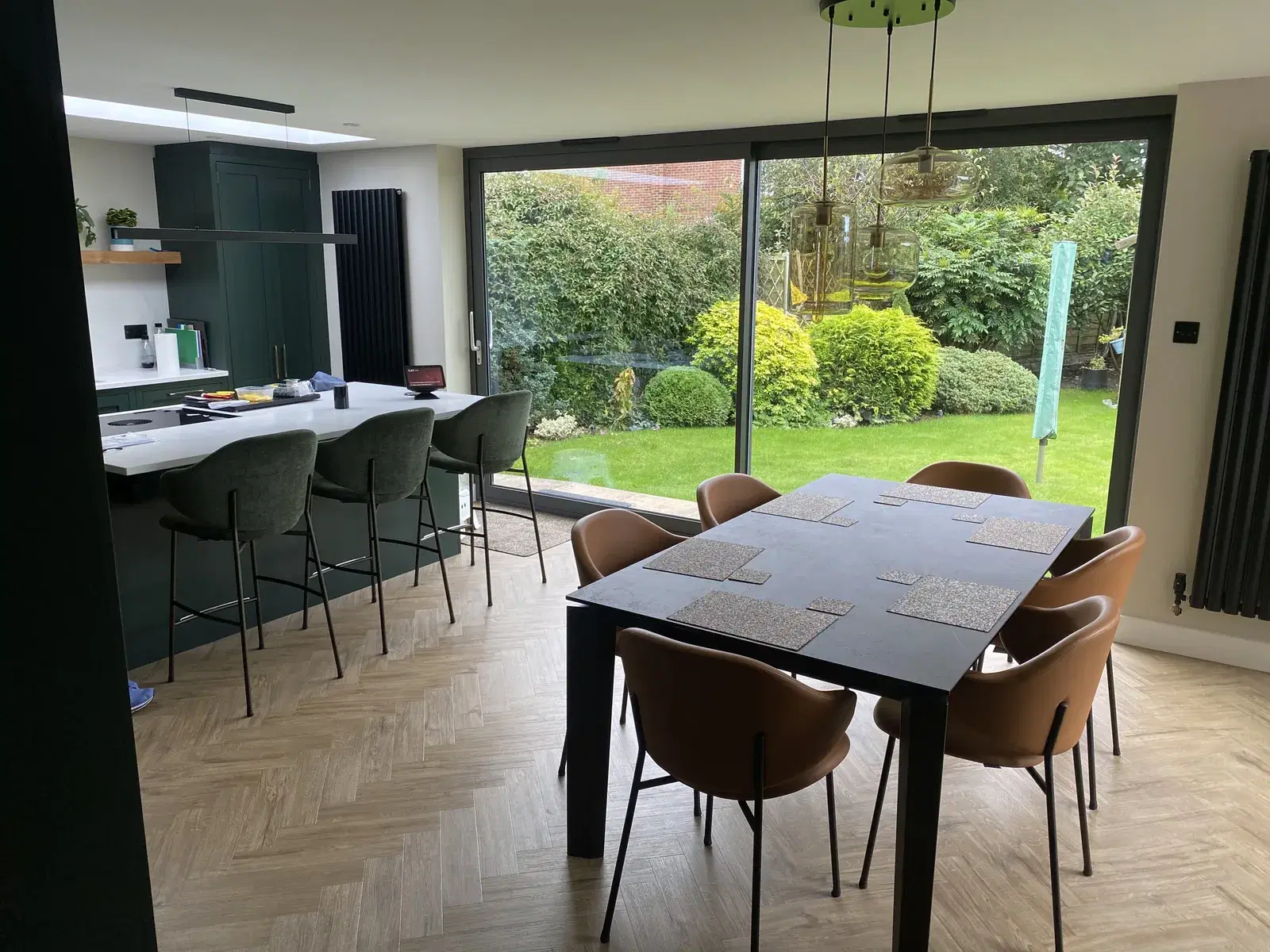 Sliding patio doors seen from inside an open-plan kitchen and dining room, looking out to a bright garden.