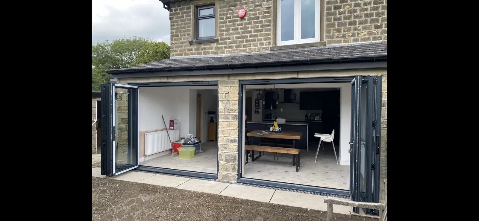 Two sets of bi-folding doors folded open across the rear of a stone house.