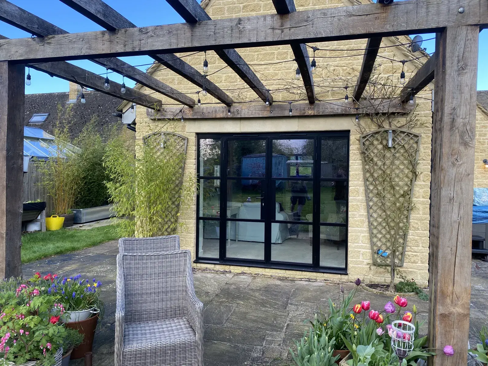 An anthracite glazed garden room built against a stone cottage, with bi-folding doors along two sides.